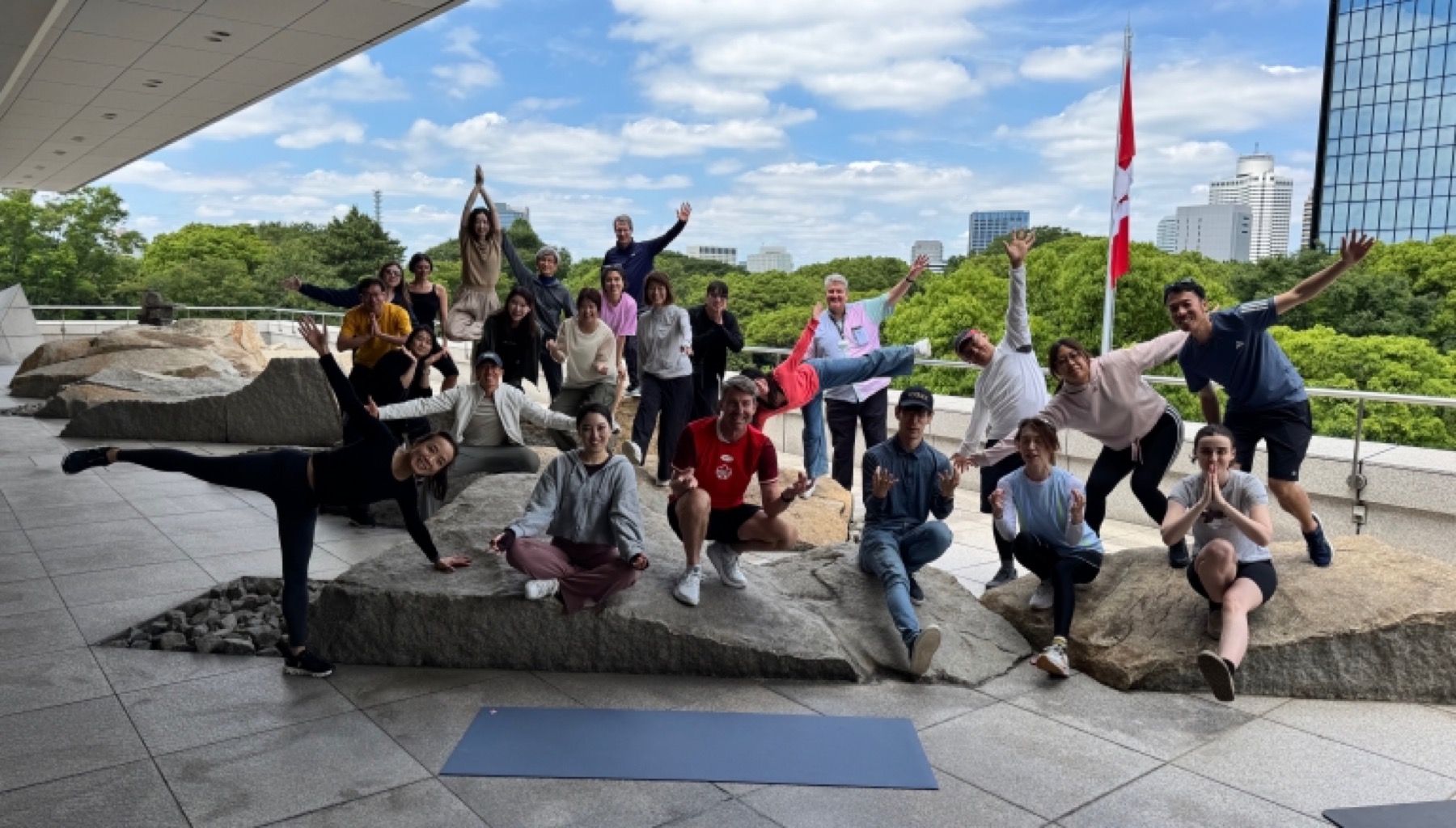Participants on the lawn of the Embassy of Canada to Japan beneath the Canadian flag after a morning of yoga and running